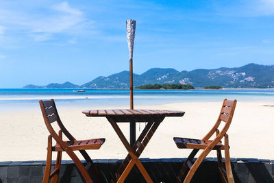 Lifeguard chair on table by sea against sky