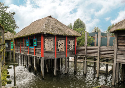 Wooden house by lake against sky