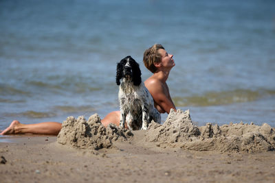 Full length of shirtless man sitting on beach