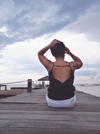 Woman with arms raised against sea against sky