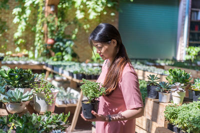 Portrait of young woman standing amidst plants