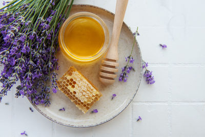 Glass of honey, honeycomb and lavender flowers