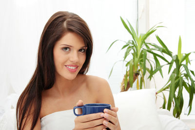 Portrait of smiling young woman holding plant
