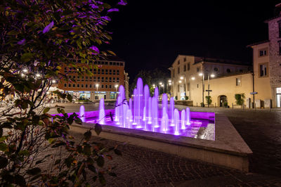 Illuminated fountain against building at night