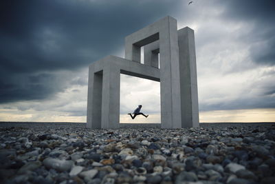 Full length of man jumping against built structure and sky