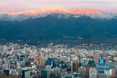 Aerial view of buildings in city against mountains during winter