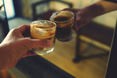 Cropped hand of person holding drink against mirror