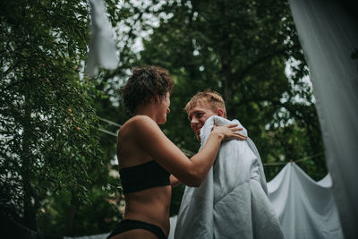 Side view of man and woman standing against trees