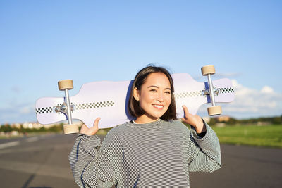 Portrait of young woman standing against clear sky