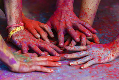 Cropped friends hands covered with powder paints during holi