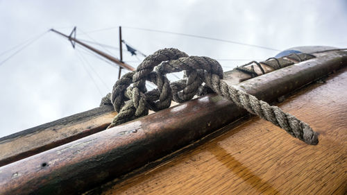 Close-up of rope tied on wood against sky