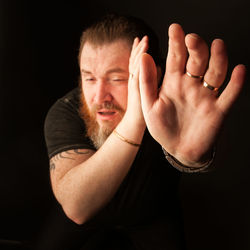 Man gesturing while standing against black background