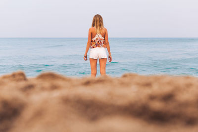 Rear view of woman standing on shore at beach