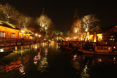 Illuminated bridge over river against sky at night