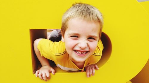 Close-up portrait of happy boy playing in yellow alphabet