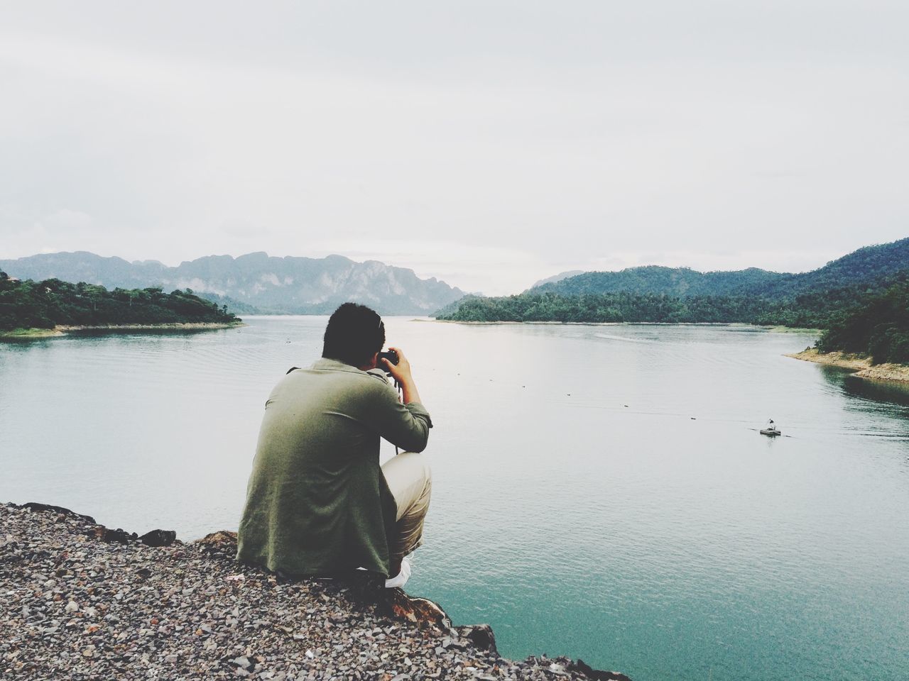 water, lifestyles, leisure activity, lake, mountain, casual clothing, rear view, sitting, tranquility, tranquil scene, standing, scenics, beauty in nature, nature, relaxation, sky, full length, getting away from it all