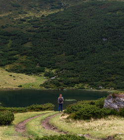 Rear view of woman standing by lake