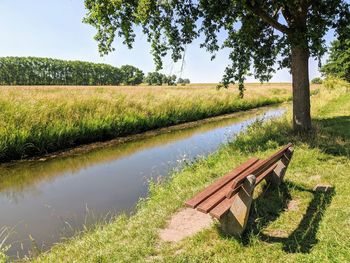 Scenic view of field by lake against sky