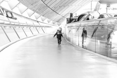 Rear view of woman walking on escalator