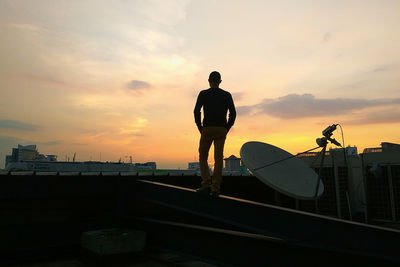 Rear view of silhouette man standing against orange sky