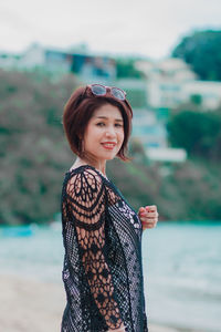 Portrait of young woman standing against sea