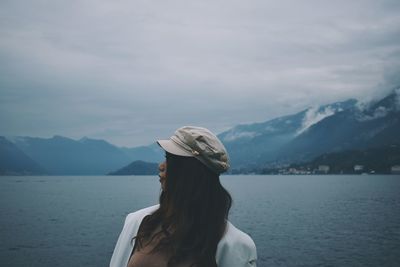 Woman looking away while standing by lake