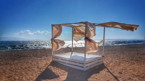 Lounge chairs on beach against clear blue sky