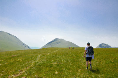 Rear view of man standing on landscape against sky