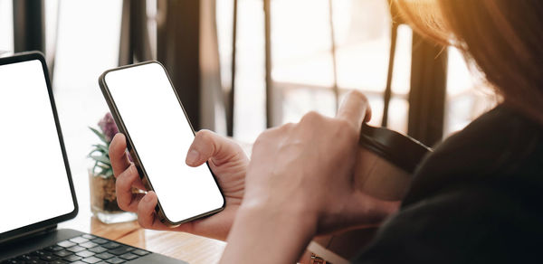 Midsection of woman holding mobile phone