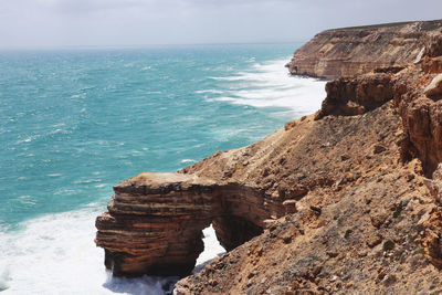 Scenic view of rock formation in sea against sky