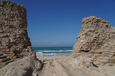 Rock formations on beach against clear blue sky