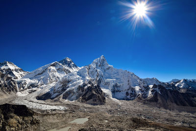 Scenic view of snowcapped mountains against blue sky