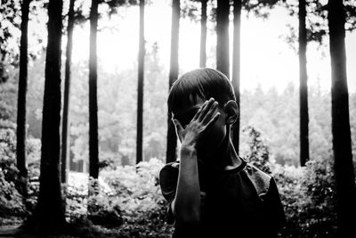 Portrait of man holding camera while standing in forest