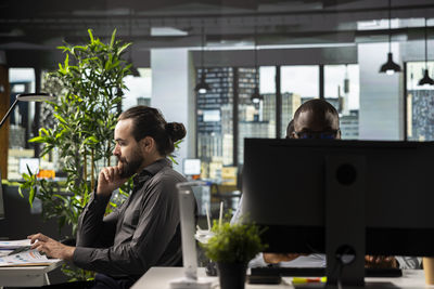 Side view of woman using laptop at office