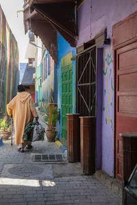 Rear view of man walking on footpath by building