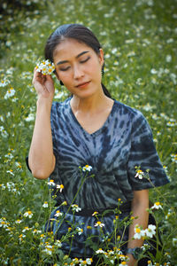 Beautiful young woman holding flower petals on land