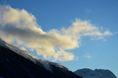 Low angle view of snow covered mountain against blue sky