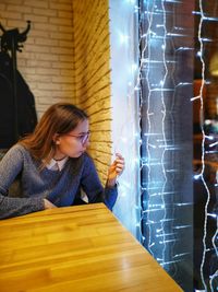 Young woman looking at fairy lights at cafe