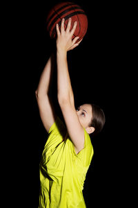 Woman playing basketball against black background