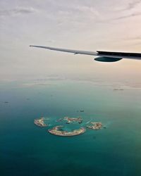 Cropped image of airplane over sea against sky