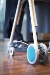 Low section of person with walker standing on hardwood floor in hospital