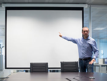 Businessman pointing on projection screen while meeting in office