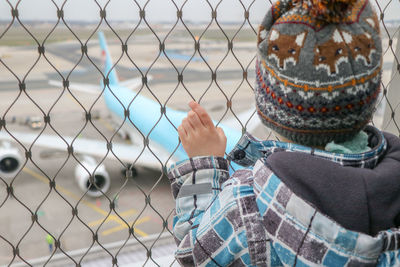 Rear view of woman standing by chainlink fence