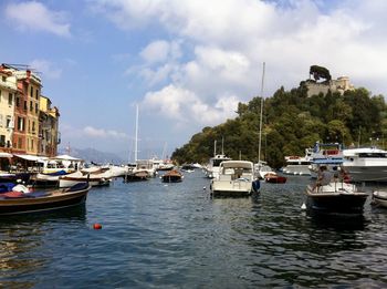 Sailboats moored on sea against sky in city