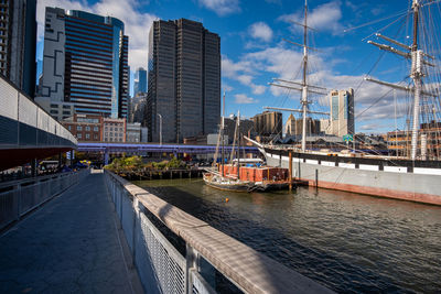 Sailboats moored on river by buildings against sky in city