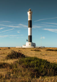 Lighthouse on field against sky