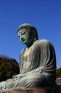 Statue of buddha against clear blue sky
