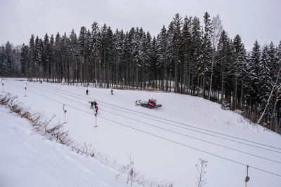 People skiing on snow covered land against sky