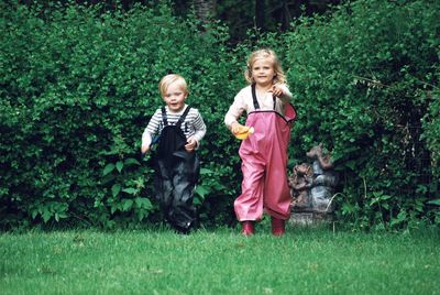 Full length of brother and sister walking on grass