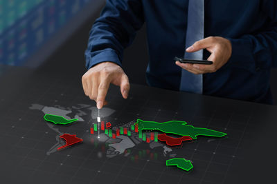 Midsection of man holding smart phone on table